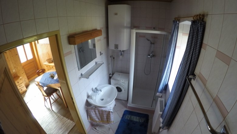 Dusche Ferienwohnung 1, © dmgrauszer Badezimmer mit Dusche, Waschbecken, Waschmaschine und blauen Vorhängen.