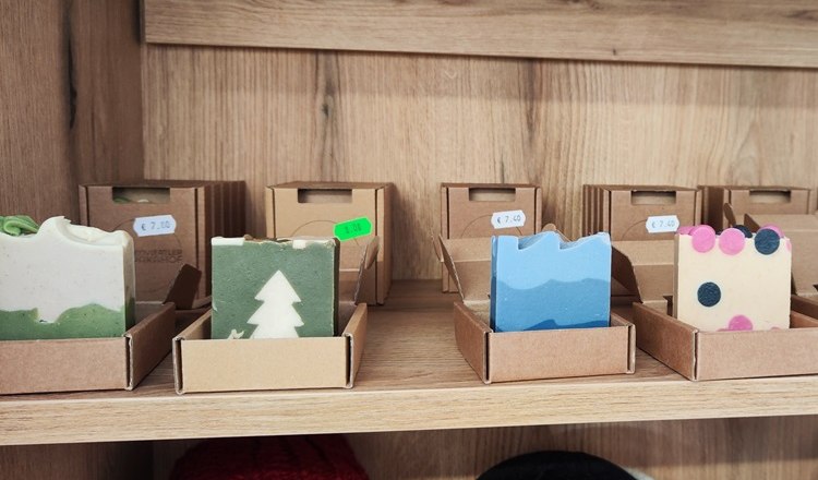 Handmade, natural soaps made from alpine wool, © Wiener Alpen Handmade soaps in different colors and patterns on a wooden shelf.