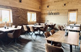 das gemütliche "dahoam" in Hollenthon, © Anita Gradwohl, dahoam Gemütlicher Gastraum aus hellem Holz mit braunen Stühlen und Holztischen.