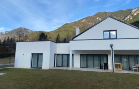 Hausansicht, © Wiener Alpen Modernes weißes Haus mit großen Fenstern vor einer Bergkulisse.