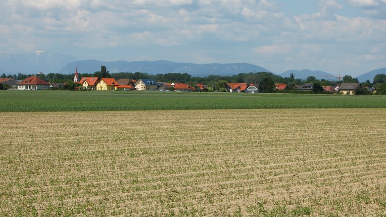Zillingdorf, © Wolfgang Glock Landschaft mit Feldern und Dorf im Hintergrund, Berge am Horizont.
