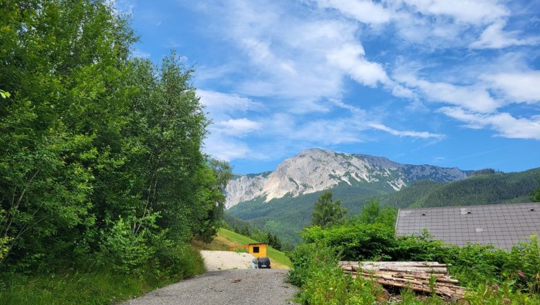 Zufahrt zum Tinyhouse, © Villa to go Zufahrt zu einem Tinyhouse in einer bergigen Landschaft mit blauem Himmel und Wolken.