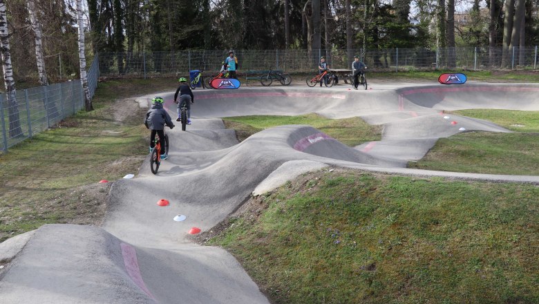 Pumptrack Neunkirchen, © Stadtgemeinde Neunkirchen Kinder fahren mit Fahrrädern auf einem Pumptrack.