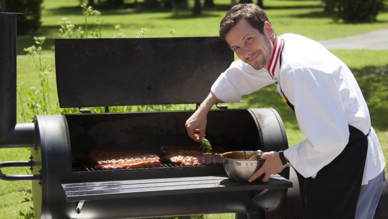 Barbecue Parkhotel Hirschwang, © Parkhotel Hirschwang A cook grills meat on a large outdoor grill.