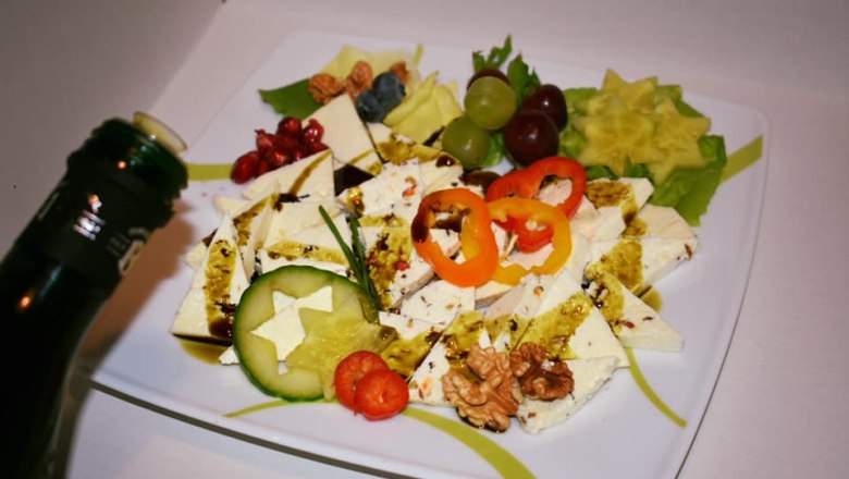Sheep's cheese from the Kölbel organic sheep farm, © Kölbel A plate of sheep's cheese, decorated with peppers, cucumber, nuts and fruit. A bottle of oil is held above it.