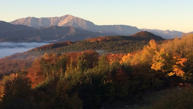..eine idyllische Lage., © Waxeneckhaus Herbstlandschaft mit bunten Bäumen und Bergen im Hintergrund bei Sonnenaufgang.