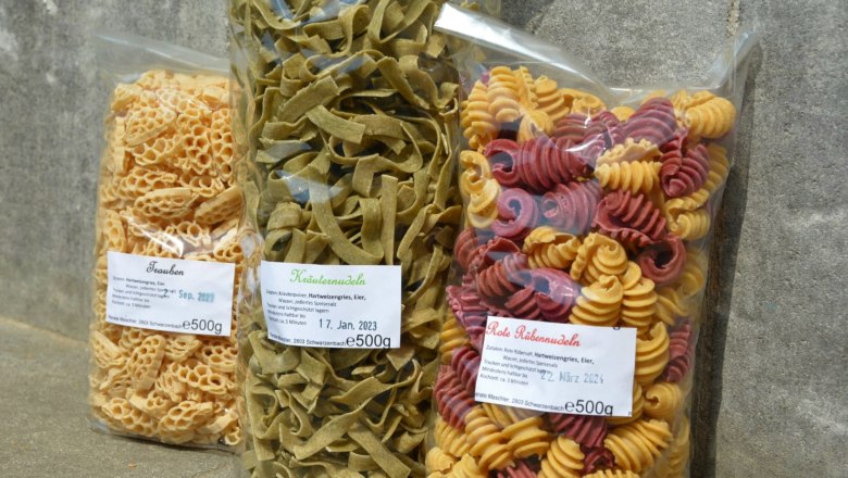Pasta variations, © Gemeinde Schwarzenbach Three packs of pasta in different shapes and colors on a stone floor.