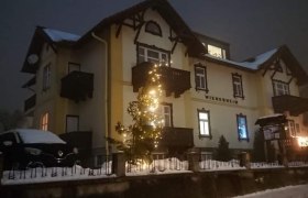 Ferienwohungen Mohr, © Familie Mohr Ein beleuchtetes Gebäude im Schnee mit Weihnachtsdekoration.