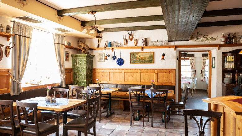 Gemütliche Stube mit Ab Hof Verkauf, © Niederösterreich Werbung/Nadja Büchler Gemütliche Stube mit Holzmöbeln, Kachelofen und Jagdtrophäen an den Wänden.