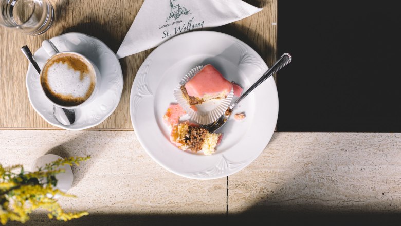 Punschkrapferl und hausgemachte Torten, © Niederösterreich Werbung/Mara Hohla Ein Teller mit einem halben Punschkrapferl und eine Tasse Kaffee auf einem Tisch.