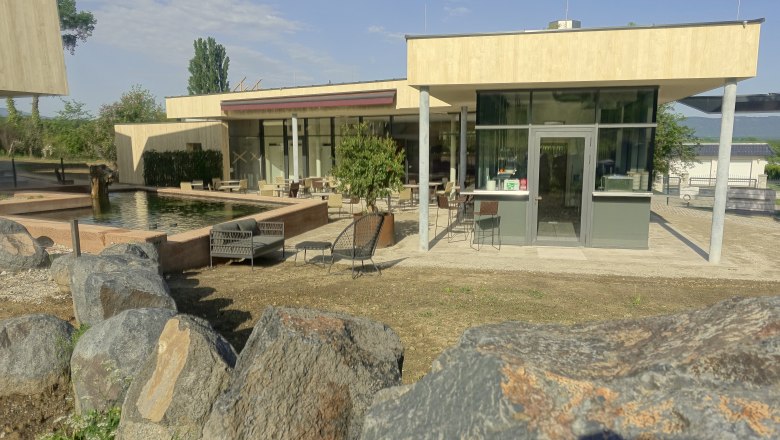 Veranda of Guntrams Manor, © Stefan M. Gergely Modern veranda with glass front and seating area, surrounded by rocks and a pond.