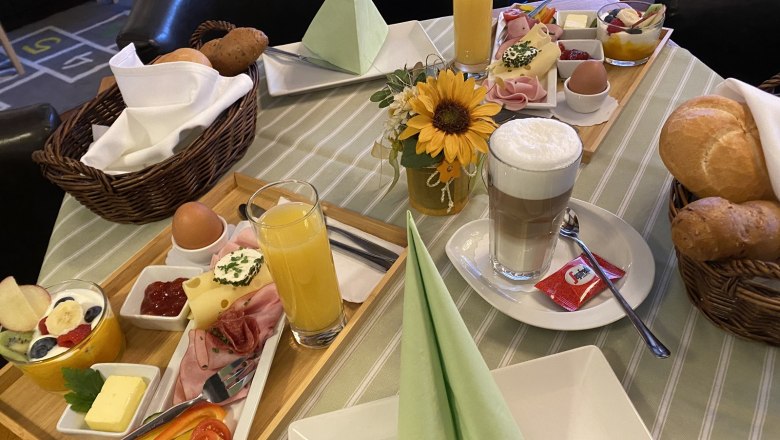 Frühstück - Pension Central, © Windbichler Ein gedeckter Frühstückstisch mit Brötchen, Aufschnitt, Eiern, Saft und Kaffee in einer Pension.