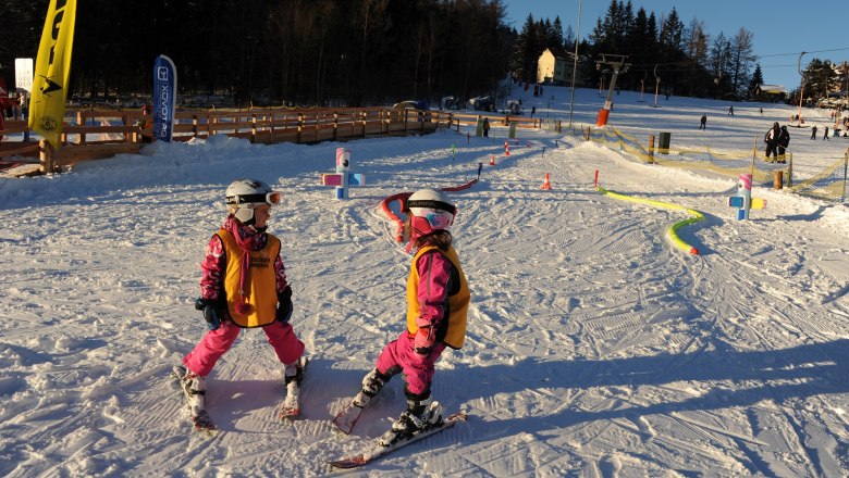 Kinderland Ski School Semmering, © Skischule Semmering Two children in ski equipment on a ski slope in the sunshine.