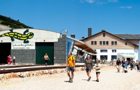 Berghaus Hochschneeberg, © Niederösterreichische Schneebergbahn GmbH, Foto Franz Zwickl Eingang der Schneebergbahn am Hochschneeberg mit Menschen und Berghaus im Hintergrund.