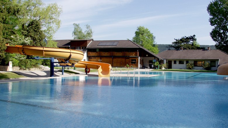 Waldbad Markt Piesting, © Isabella Palfy Ein Freibad mit Rutsche und Gebäuden im Hintergrund.