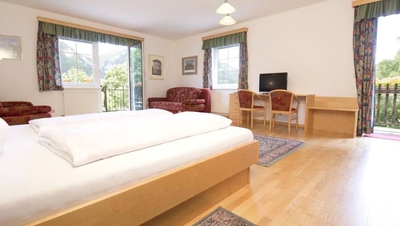 Familienzimmer, © Flackl Wirt_Mediaharmonists Doppelzimmer mit Holzboden und roter Couch sowie bunten Vorhängen