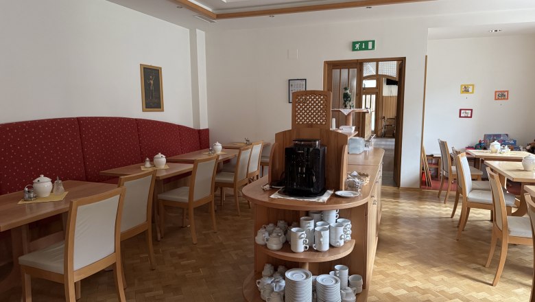 Hotel Zur Alten Schule, © Viregro Capital Gmbh Innenansicht eines Frühstücksraums mit Holzmöbeln und Geschirr.