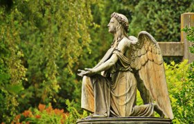 Friedhof, © gemeinfrei Engelsstatue auf einem Friedhof, umgeben von grüner Vegetation.