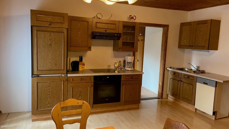 Kitchen Apartment 1, © Wiener Alpen Kitchen with wooden furniture, dining table and chairs, stove, sink and dishwasher.