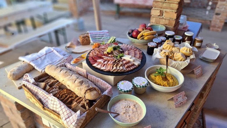 Regionale Speisen beim Sonntagsbrunch, © Anita Brem-Hofer Ein Buffet mit Brot, Aufschnitt, Obst, Marmeladen und Dips auf einem Tisch.