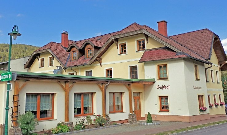 Spacious rooms and guest garden for parties, © Wiener Alpen A traditional inn with a yellow façade and red roofs.