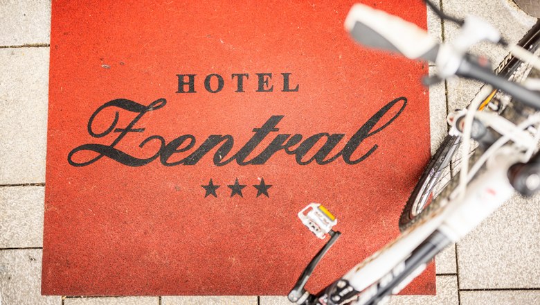 Eingangsbereich des 3-Sterne Hotels , © Wiener Alpen/Fülöp Eingangsbereich mit Fußmatte mit Aufschrift Hotel Zentral und abgestelltem Rad