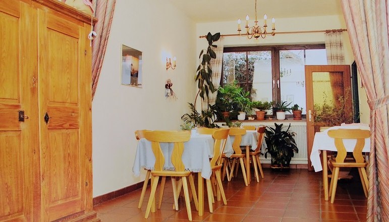 Speisezimmer, © Wiener Alpen Ein gemütliches Speisezimmer mit Holzmöbeln, Pflanzen und einem Kronleuchter.