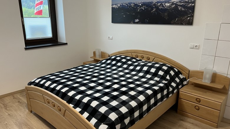 Schlafzimmer mit Doppelbett, © Anton Sommer Schlafzimmer mit Doppelbett, kariertem Bettbezug und Bergbild an der Wand.