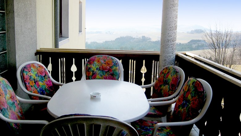 Balcony, © Anke Spreitzer Balcony with table and colorful chairs, view of the countryside.