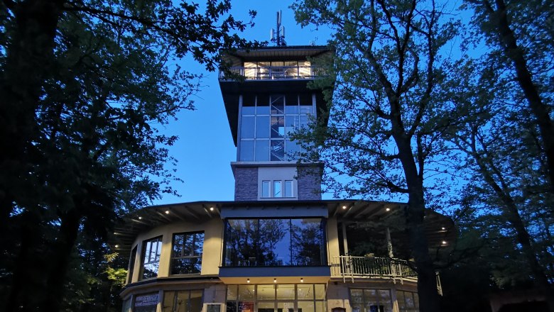 Turmcafé Schwarzenbach bei Nacht, © Gemeinde Schwarzenbach. Ovales Gebäude mit Aussichtsturm aus Glas bei Nacht.