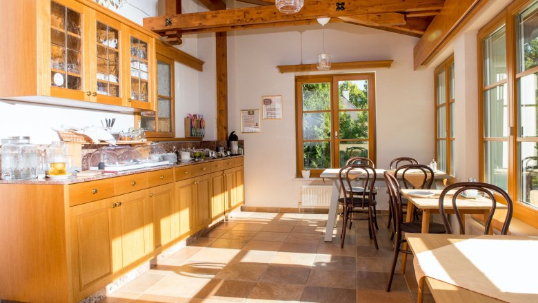 Frühstücksbuffet, © Dorfschmiede eG Ein heller Raum mit Holzmöbeln, Frühstücksbuffet und Tischen am Fenster.