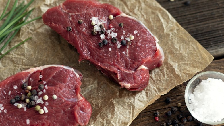 Rindfleisch vom Angus-Weiderind, © Fam. Luckerbauer Zwei Stück rohes Rindfleisch mit Salz und Pfeffer bestreut auf Backpapier, daneben Schnittlauch, eine Schale Salz und Pfeffer.