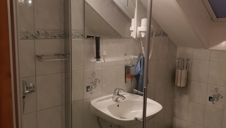 Duschraum, © Reep Ein Badezimmer mit Dusche, Waschbecken, Spiegel und Dachfenster.