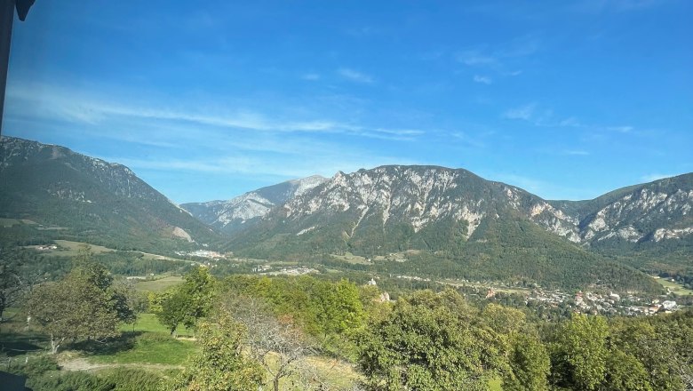 Blick aus der Ferienwohnung, © Manuel Leitmaier Blick auf eine Berglandschaft mit blauem Himmel und grünen Wiesen.