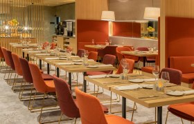 Restaurant, © Hilton Garden Inn Wiener Neustadt Innenansicht eines modernen Restaurants mit gedeckten Tischen und roten Stühlen.