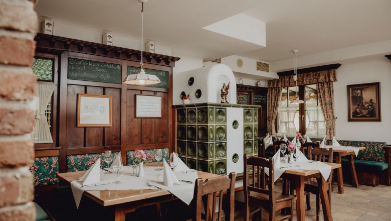 Heimeliges Traditionshaus am Fuße des Schneebergs, © Niederösterreich Werbung/Rita Newman Gemütliches Restaurant mit Holzmöbeln, Kachelofen und dekorierten Tischen.