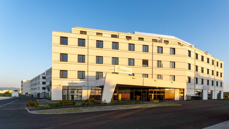 Plaza INN, © Plaza INN A modern, multi-storey building with the inscription 'Plaza INN' at sunset.