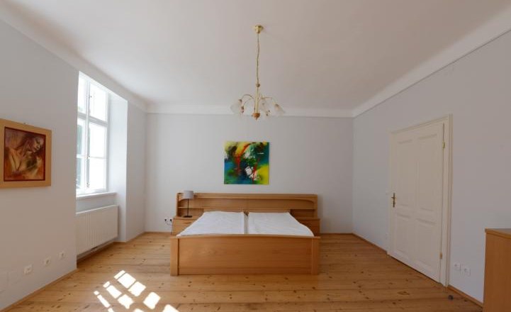 Apartment G1 in the Gerhardthof Reichenau, © Gerhardthof Reichenau Bedroom with wooden floor, double bed, two paintings and a window.