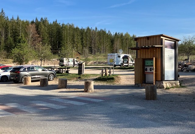 stellplatz-naturpark-zentrum-hohe-wand-3, © Naturpark Hohe Wand Parkplatz am Naturparkzentrum Hohe Wand mit Autos und Wohnmobilen, umgeben von Wald.