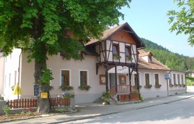 Gasthaus Auerhahn, © Marktgemeinde Schottwien Traditionelles Gasthaus, davor Blumenkästen, umgeben von Bäumen.
