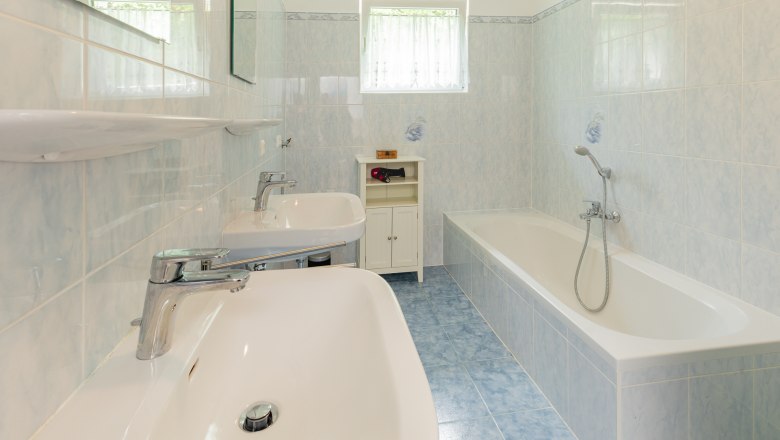 Badewanne, © Wiener Alpen / Christian Kremsl Ein Badezimmer mit zwei Waschbecken, einer Badewanne und blauen Fliesen.