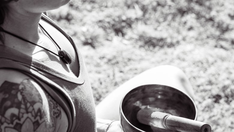 Asanas-Pranayama-Meditation-Achtsamkeit, © Yoga.imEinklang Person hält eine Klangschale im Freien.