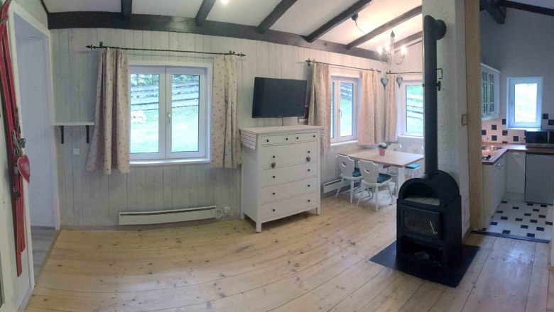 Ferienhaus, © Marianne Gschaider Innenansicht eines gemütlichen Ferienhauses mit Holzofen, Esstisch und Küche.