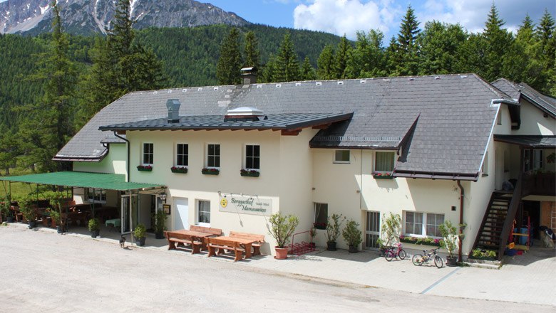 Berggasthof Mamauwiese, © Berggasthof Mamauwiese, Bernhard Wilsch Berggasthof Mamauwiese vor bewaldeten Bergen.