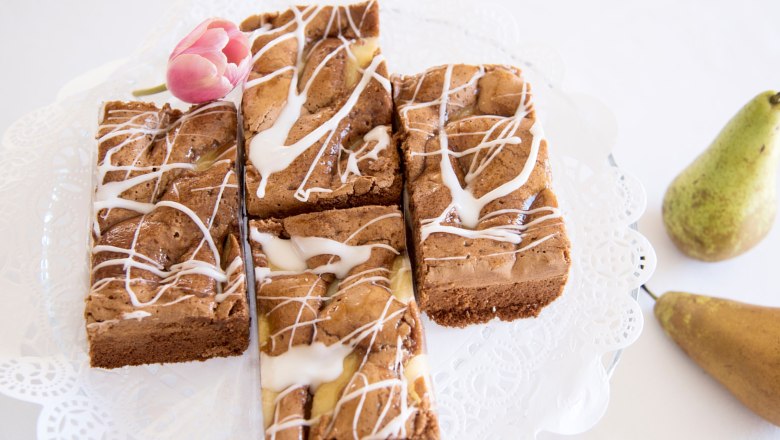 Hausgemachte Mehlspeise, © Stadtcafé Gloggnitz Hausgemachte Mehlspeise mit Zuckerguss und Tulpe als Dekoration, daneben Birnen.