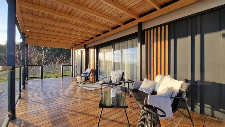 Terrasse Johannesbachklamm Chalet, © Johannesbachklamm Chalet Moderne Terrasse mit Holzboden, Glasgeländer und gemütlichen Sitzmöbeln.