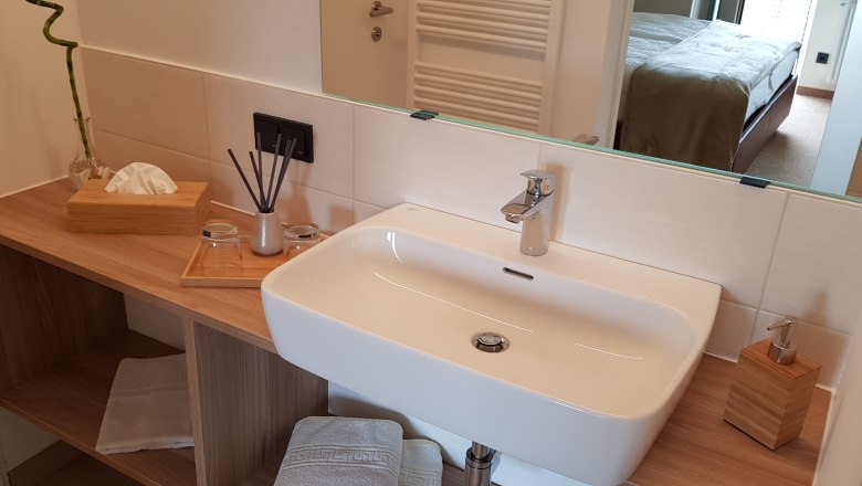 Badezimmer, © Alexandra Heiling-Niegl Modernes Badezimmer mit Waschbecken, Spiegel und Holzablage.