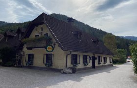 Gasthof Brandstätterhof, © Wiener Alpen Traditionelles Gasthaus mit Blumenbalkon vor bewaldeten Hügeln.