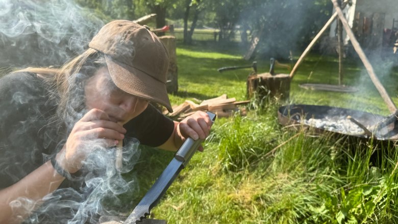 Survival Workshop Wildnis Zentrum Nasswald, © Georg Bergthaler Person entzündet Feuer mit Messer und Holz im Freien.