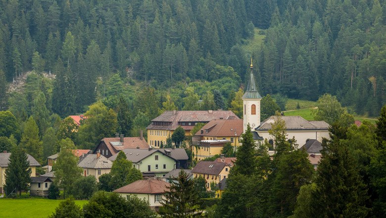 Blick auf Rohr im Gebirge, © Wiener Alpen, Christian Kremsl Ein Dorf mit Kirche inmitten von bewaldeten Bergen.